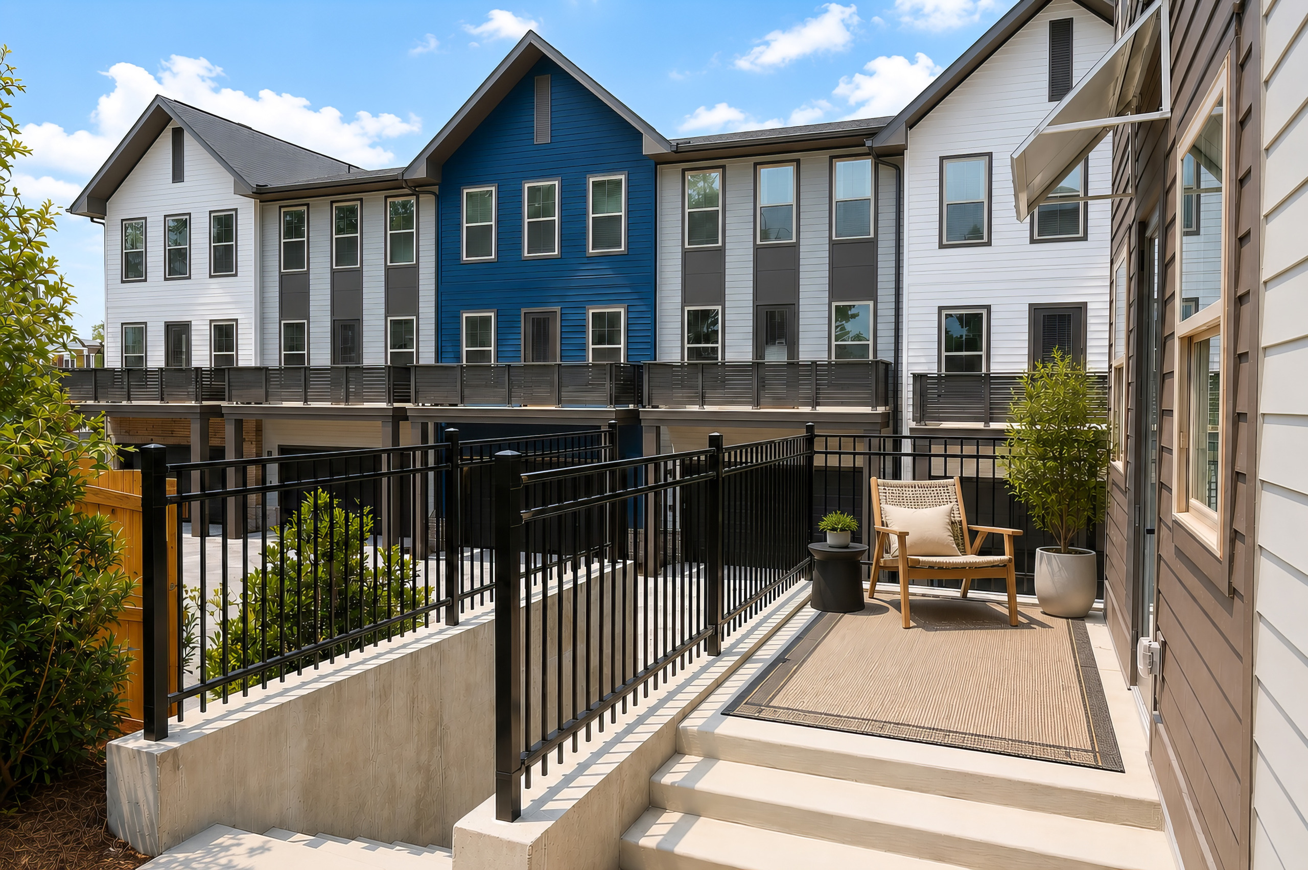 Completed Woodrow House townhomes with private patios, blue-and-white facades, and landscaped courtyards.