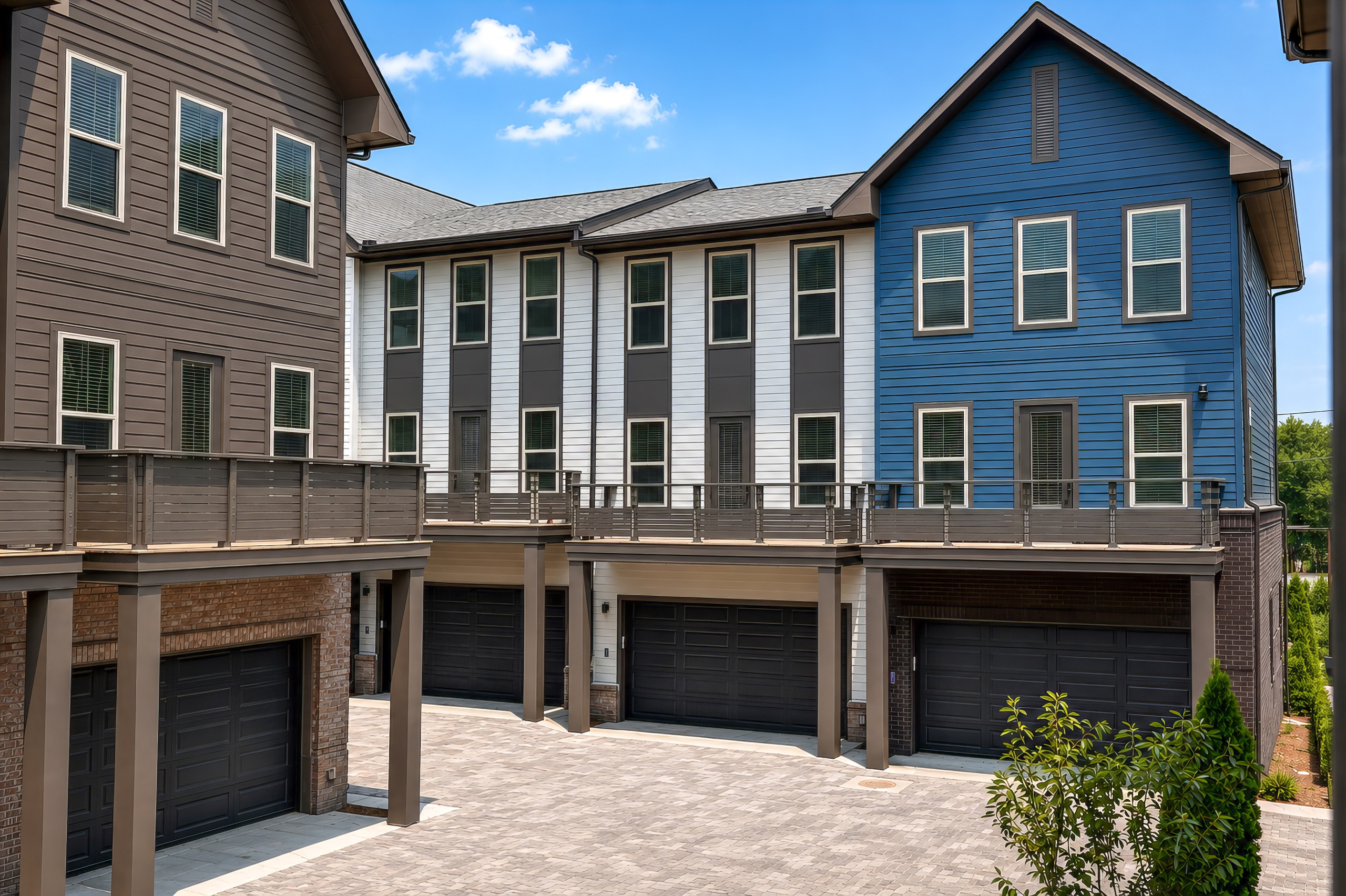 Completed three-story Woodrow House townhome facades with blue, white, and gray siding above private garages.