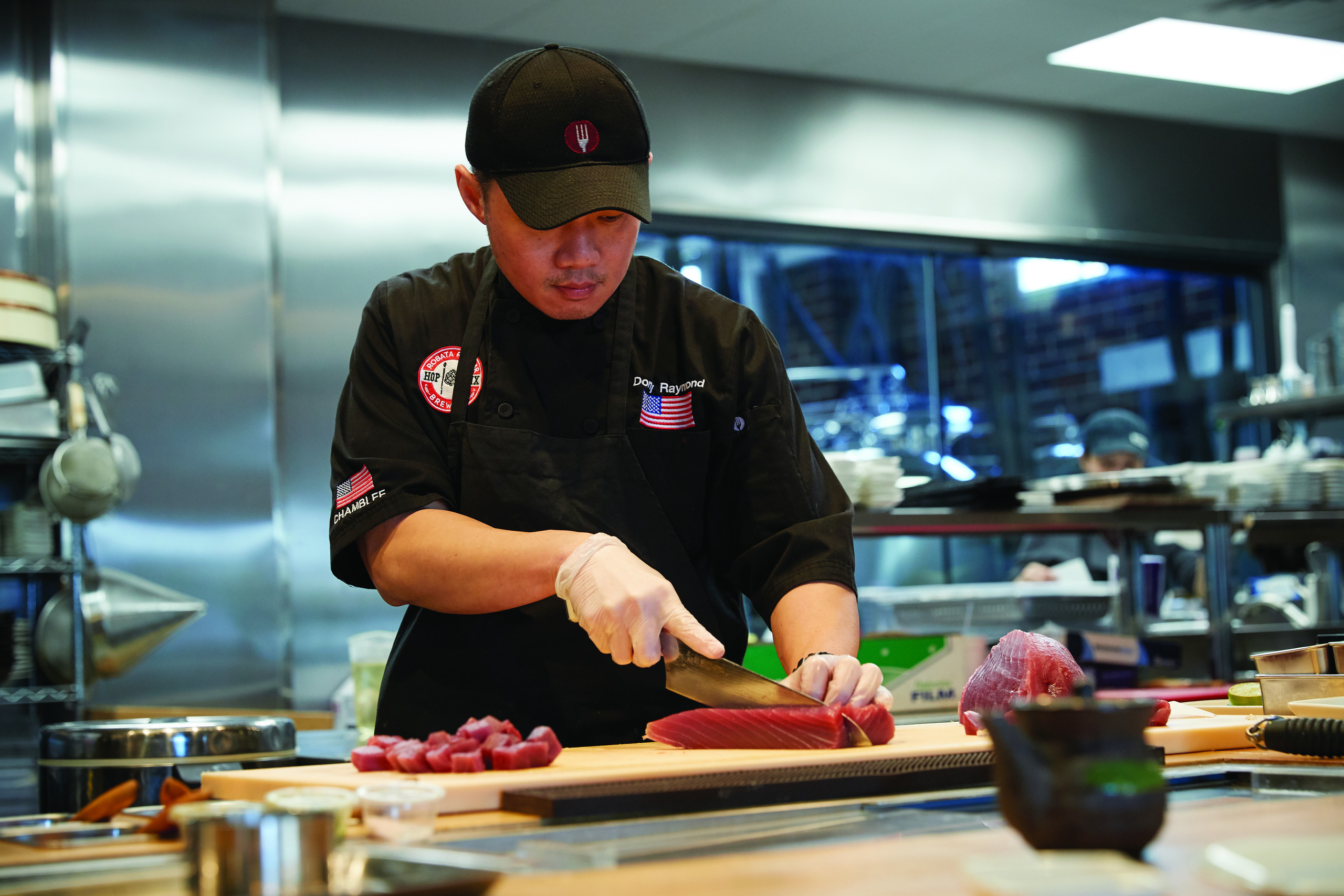 A man cuts up fish in the kitchen of the Hopstix restaurant in Chamblee.