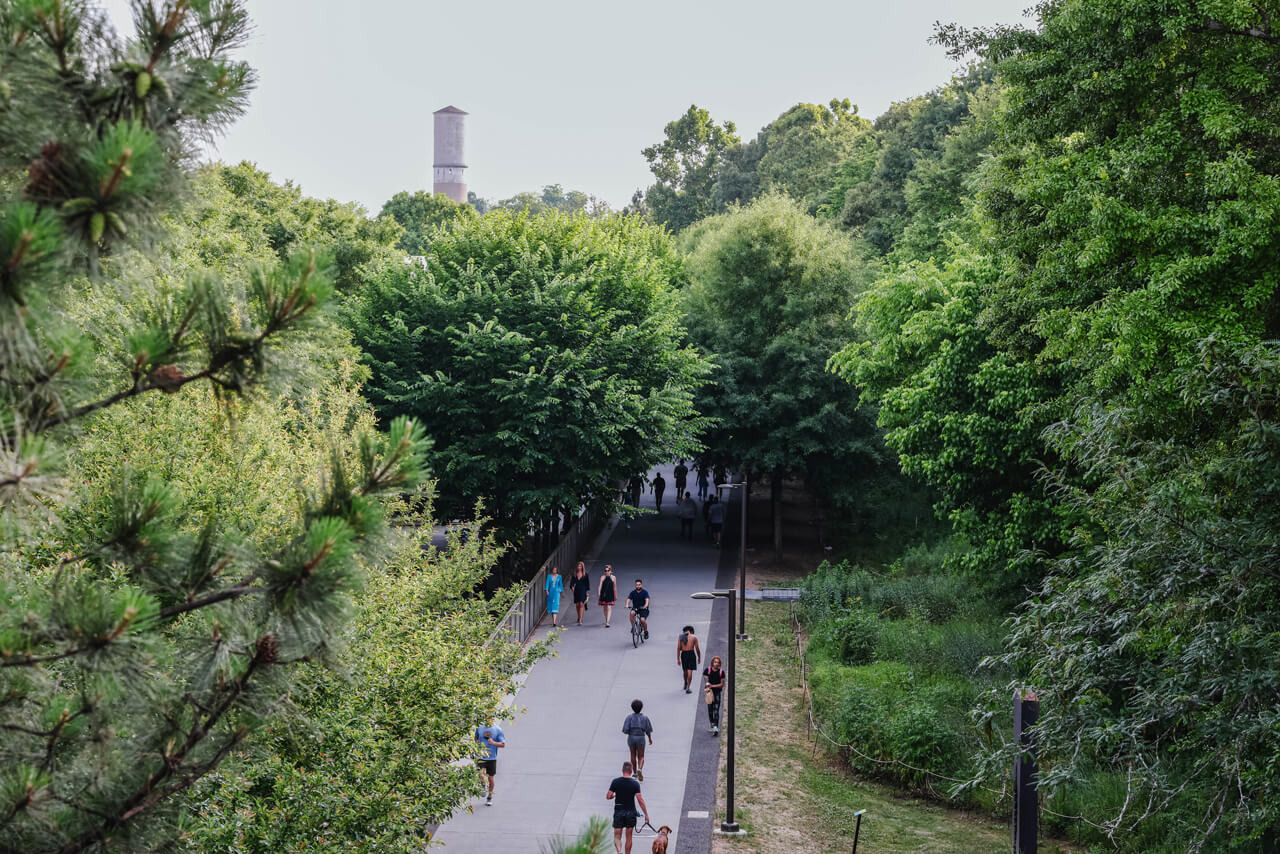 People walking & biking along a tree-lined paved trail