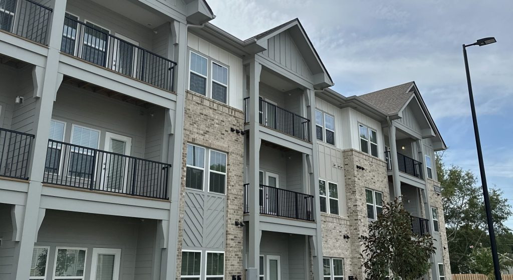 Meadow Glen Village apartment building with balconies, pale siding and brick facade.
